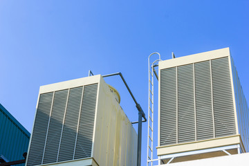 Industrial cooling towers or air cooled chillers on new building factory rooftop with blue sky background