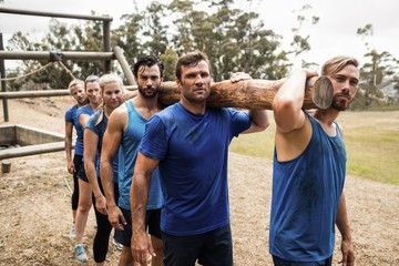 Wall Mural - People carrying a heavy wooden log during boot camp