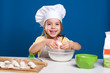© aemstock - The little girl is cooking and preparing food on blue background