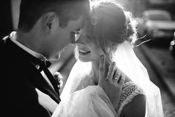 Brunette groom holds bride in lace corset tender standing with her in the rays of evening light