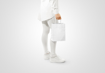 Wall Mural - Blank white craft paper bag design mockup holding hand. Woman hold kraft textured purchase pack mock up isolated. Clear shop bagful branding template. Shopping carry package in persons arm.
