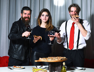 Happy friends toasting glasses and eating pizza