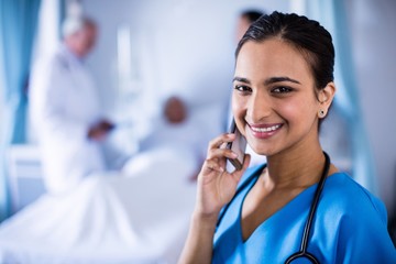 Wall Mural - Smiling female doctor talking on a mobile phone