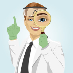 young doctor with magnifying glass and safety goggles pointing up