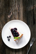 Slice of cheesecake with blueberry and black currant on white plate over wooden background. Top view with copy space for your text