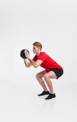 Wall Mural - Fitness man holding medicine ball, doing squat, studio shot.