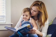 © Cavan Images - Mother and daughter sitting together and reading book