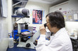 © Cavan Images - Female scientist looking through microscope in laboratory