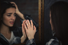 Depressed Young Woman Looking On Her Reflection In Mirror