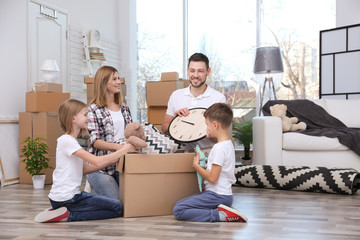 Poster - Happy family unpacking cardboard box on floor in new house