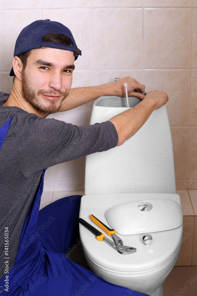 Plumber repairing toilet cistern at water closet