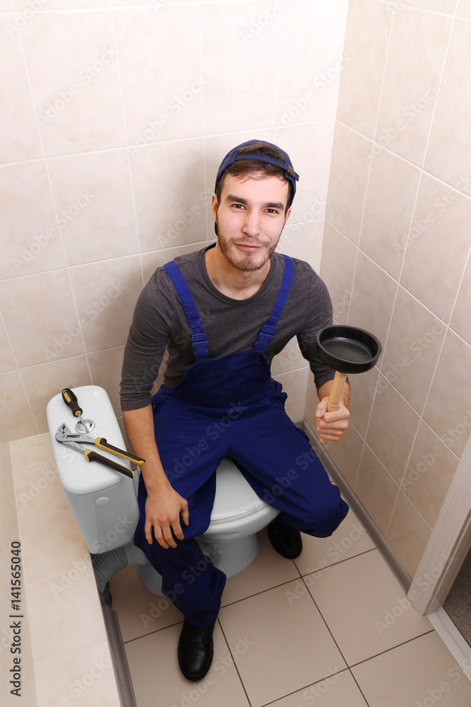 Plumber with hand plunger in bathroom