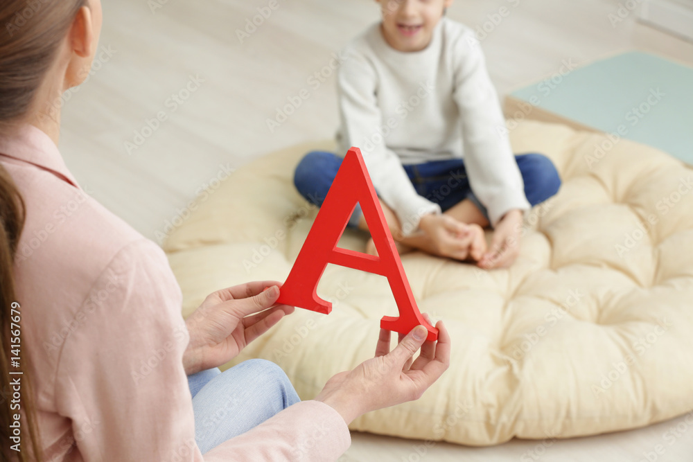 Speech therapist with letter A and blurred boy on background