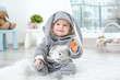 © Africa Studio - Cute little baby in bunny costume sitting on furry rug and eating carrot