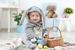 © Africa Studio - Cute little baby in bunny costume playing with Easter eggs at home