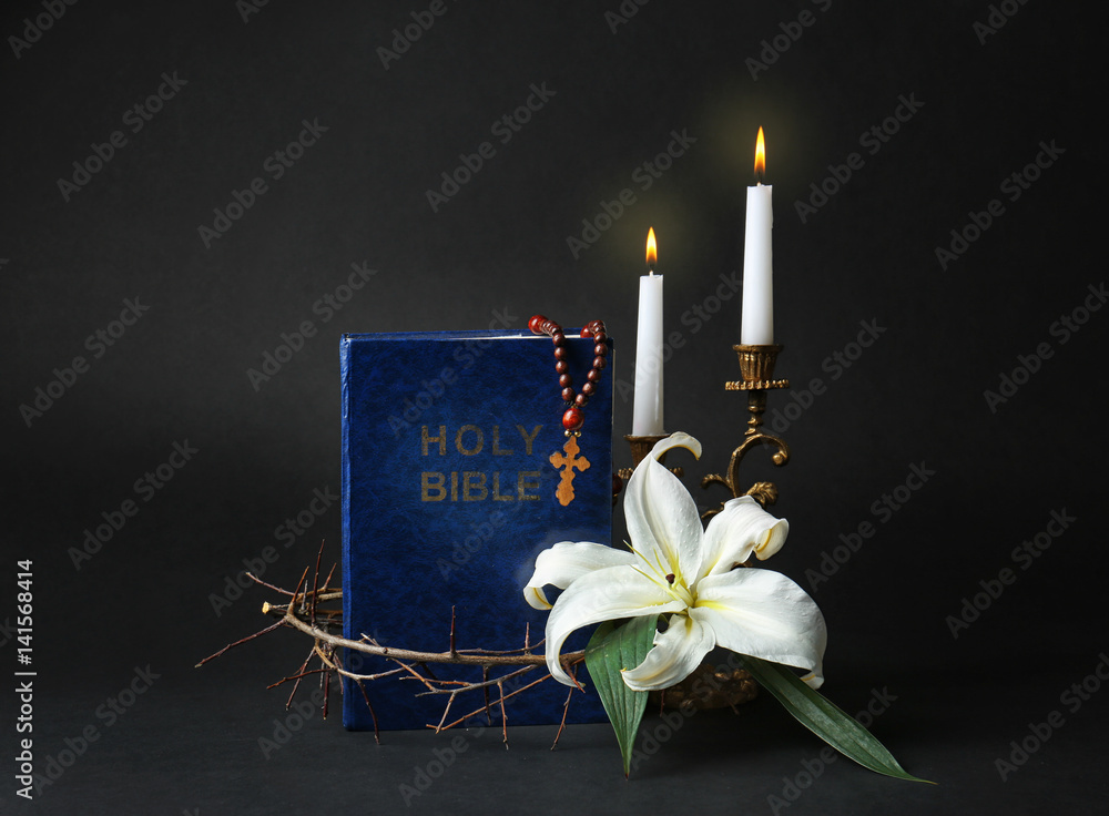 Holy Bible, crown of thorns and Easter white lily on dark background