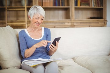 Wall Mural - Senior woman using mobile phone in living room