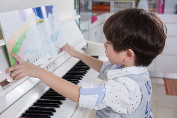 Asian Chinese little boy playing piano at home