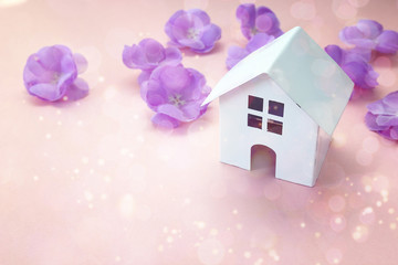 Wall Mural - Miniature white toy house with purple flowers on pink background.