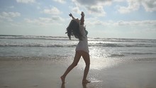 Young Beautiful Girl Enjoying Life And Having Fun At Sea Shore. Happy Woman Walking On The Beach Near The Ocean. Summer Vacation Or Holiday. Nature Landscape At Background. Slow Motion