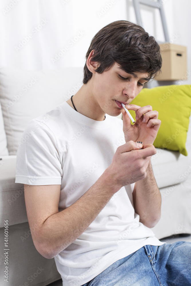 young guys smoking cigarettes Young man smoking a cigarette. Teenage boy lighting a cigarette Stock Photo