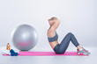 © Rychko Yevhen - beautiful blonde girl in sportswear does exercises on fitness Mat on gray background