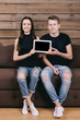 © luckyphoto - smiling couple sitting on coach with digital tablet