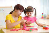 Fototapeta  - Child girl and mother playing with kinetic sand at home