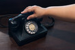 © pomphotothailand - Catch the phone handle antique old black rotary telephone on the wooden table