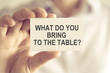 © stanciuc - Businessman holding WHAT DO YOU BRING TO THE TABLE ? message card