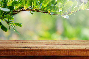 Wall Mural - Wooden table and green leaf nature background.