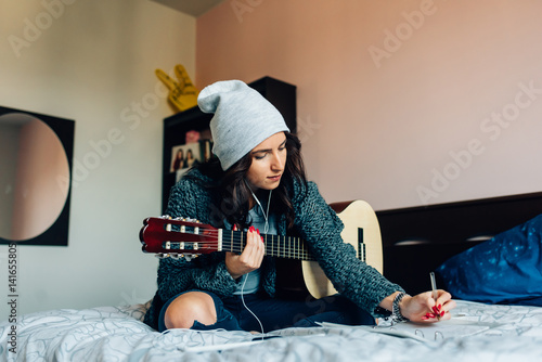 Young Beautiful Woman Composing A Song Sitting On Her Bed In