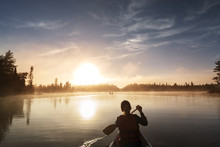 Rear View Of Woman Traveling In Boat On Calm Lake Against Sky