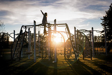 Girl Playing On Metallic Structure At Park Against Cloudy Sky