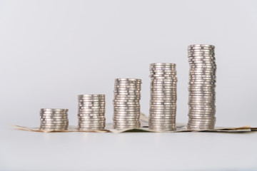 Increasing columns of coins, piles of coins arranged as a graph and dollar currency on white background.