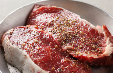 Canvas Print - Raw steaks with spices in bowl, closeup