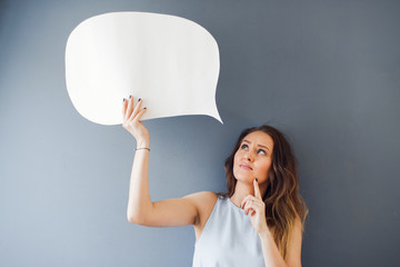 Portrait of a young woman posing with a speech bubble against a gray background
