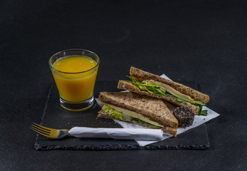 set consisting of two sandwiches malted bread with vintage cheddar cheese, pickles, red onion, tomato, lettuce, orange juice