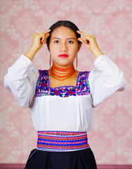 Wall Mural - Young woman wearing traditional andean dress, facing camera doing sign language word for graduated