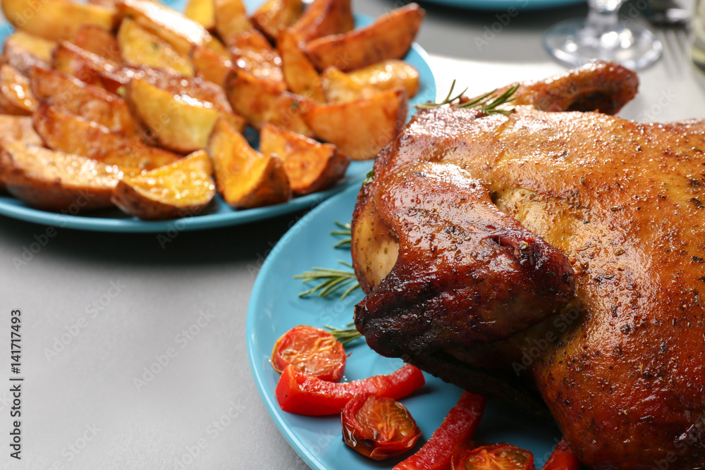 Plate with roasted beer can chicken on gray table
