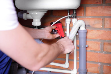 Sticker - Plumber repairing sink pipes in kitchen, closeup