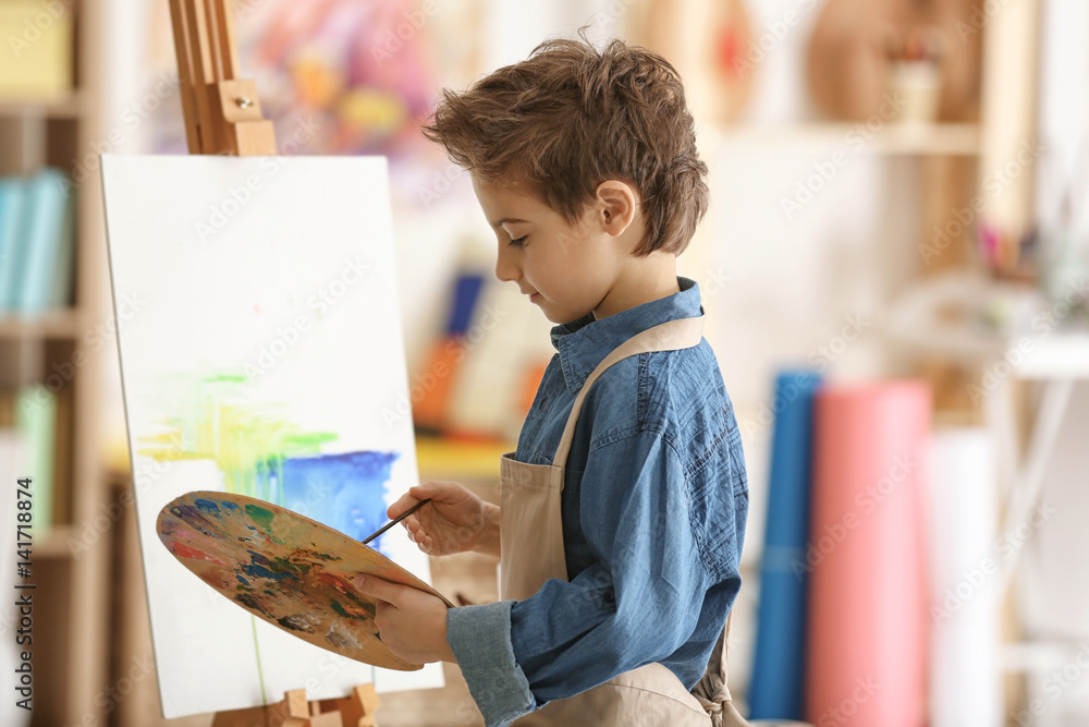 Cute little artist painting picture in studio