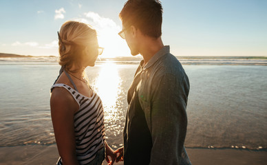 Wall Mural - Couple on beach looking at the sunset