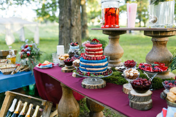 Wall Mural - Wedding in the forest. cake with berries, Blueberries and raspberriess on the table. Fourchette, a lot of food on the table