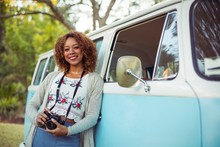 Woman Leaning On Campervan With Camera