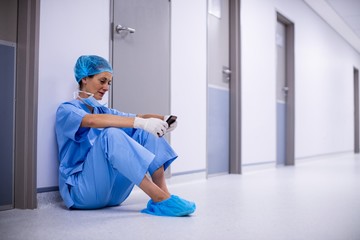 Wall Mural - Surgeon sitting on floor and using mobile phone