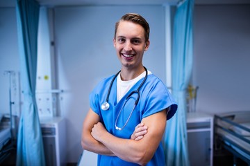 Poster - Portrait of male doctor standing with arms crossed in ward