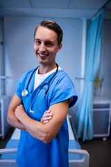 Wall Mural - Portrait of male doctor standing with arms crossed in ward