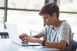 © WavebreakMediaMicro - Schoolboy using laptop in classroom