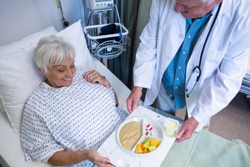 Wall Mural - Doctor serving breakfast and medicine to senior patient